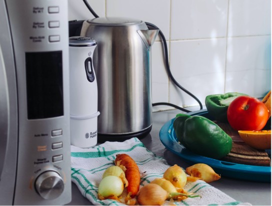 Three kitchen appliances sitting next to vegetables on a kitchen towel